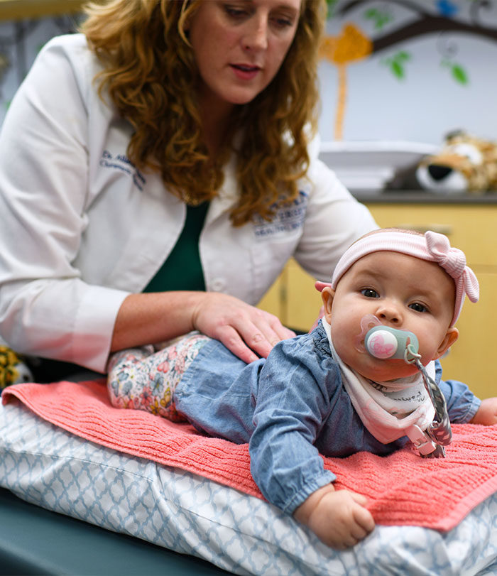 Pediatric chiropractor adjusting baby.